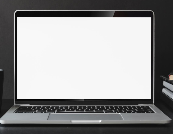 A white computer screen with a cup of coffee to the left, and a pile of 
            unknown books to the right.